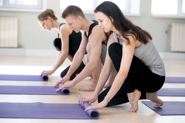 Persone che si preparano per la classe di yoga srotolamento stuoie — Foto Stock