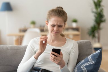 Sinir bozucu kadın kanepede oturan smartphone bakarak