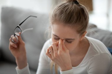 Woman taking off eyeglasses massaging nose bridge clipart