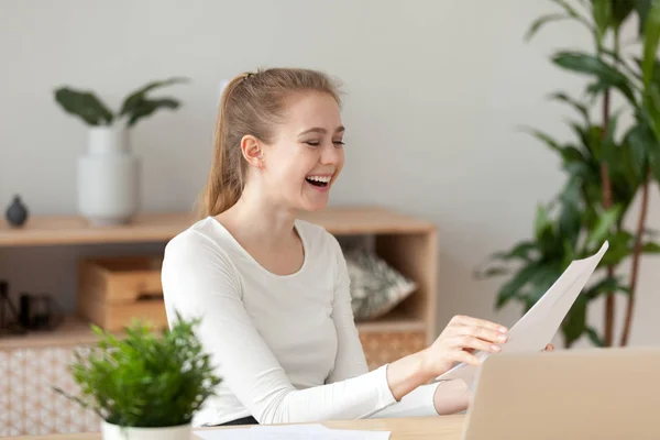 Glad skrattande kvinna sitter vid skrivbordet läsa dokument — Stockfoto