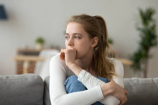 Sad woman sitting on couch alone at home — Stock Photo, Image