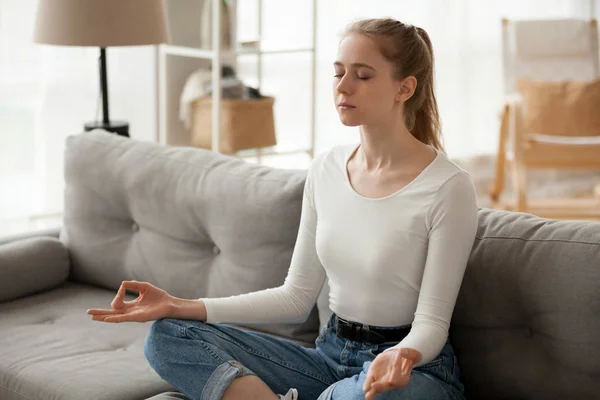 Woman meditating sitting on couch at home — Stock Photo, Image