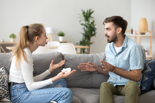 Coupe emotionally arguing sitting on couch at home