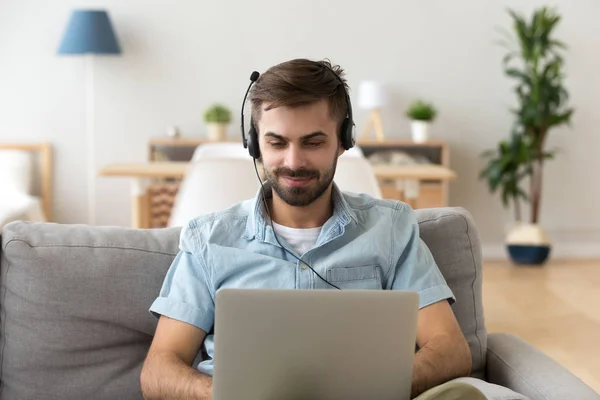 Człowiek za pomocą zestawu słuchawkowego i studia pracy laptopa w domu — Zdjęcie stockowe