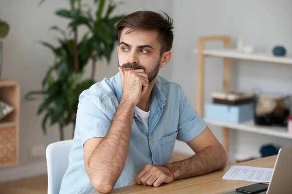 Young thoughtful man sitting at the desk — Stock Photo, Image