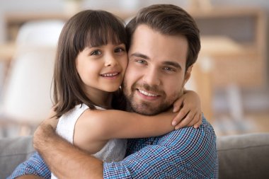 Baba ve kızı oturan kucaklayan kameraya bakarak kanepe