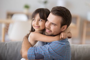 Baba ve kızı oturan kucaklayan kameraya bakarak kanepe