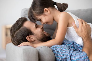 Kızı ve babası koltukta yan yana yatarken gülümseyen