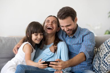 Video gülüyor izlerken smartphone kullanarak kanepede oturan aile