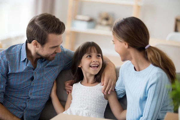 Daughter sitting together with parents on couch in living room