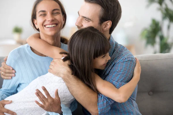Rozkošný předškolní dcera objímat šťastný usmívající rodiče — Stock fotografie