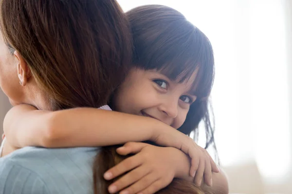 Happy daughter looking at camera embracing mother — Stock Photo, Image