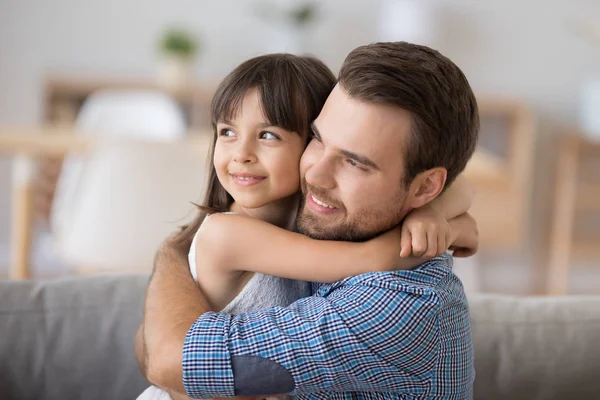 Père et fille embrassant assis sur le canapé regardant la caméra — Photo