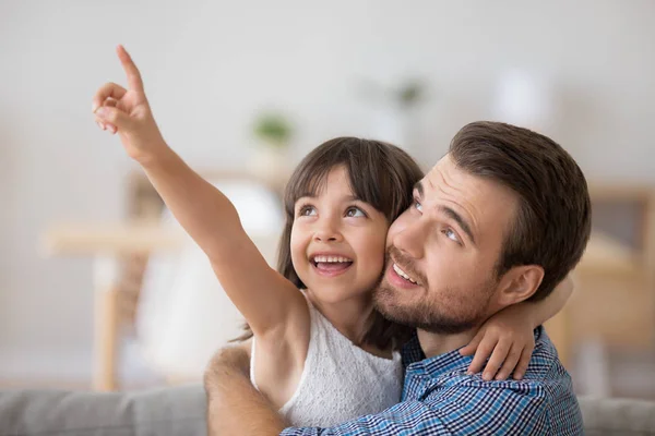 Dochter omarmen met vader met haar hand linksboven te wijzen — Stockfoto