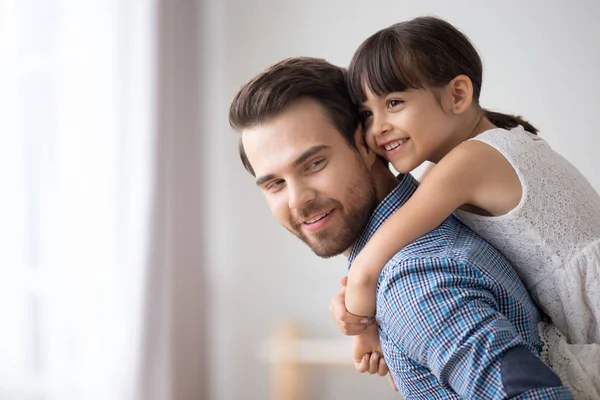 Father hold daughter piggyback standing in living room — Stock Photo, Image