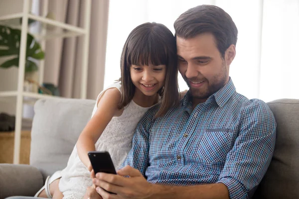 Отец и маленькая дочь проводят свободное время, пользуясь смартфоном — стоковое фото