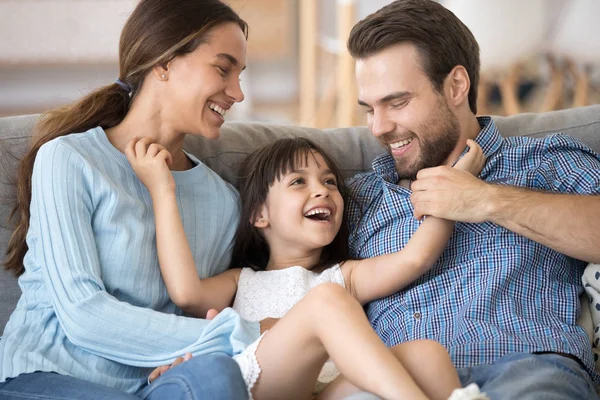 Allegro figlia solletico genitori famiglia seduta su divano — Foto Stock