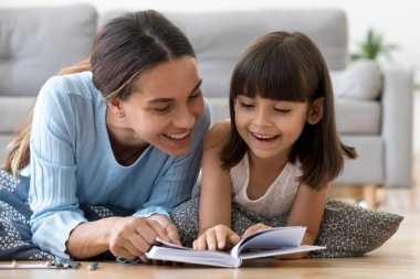 Anne ve kızı kitap okuma sıcak yerde yatarken