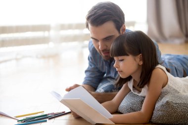 Baba ve kız kitap okuma sıcak yerde yatarken