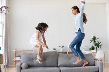 Anne ve küçük kızı eğleniyor kanepeye atlama
