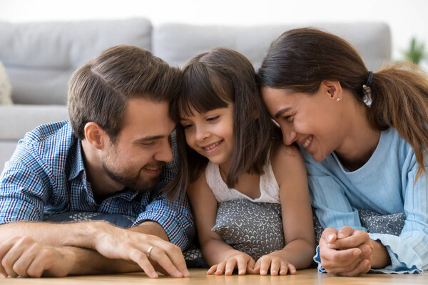 Cheerful diverse family lying on warm floor at home