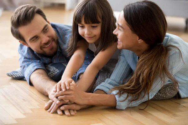 Diversa famiglia sdraiata sul pavimento caldo tenendosi per mano — Foto Stock