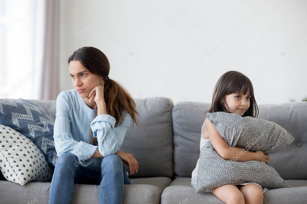 Daughter and mother after quarrelling sitting on couch