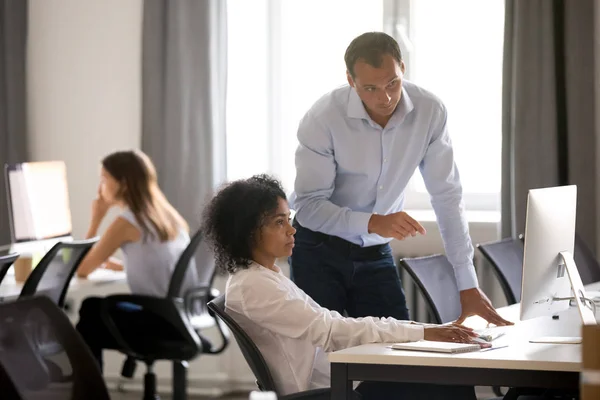 Männlicher kaukasischer Mentor erklärt weibliche afrikanische Praktikantin online ta — Stockfoto