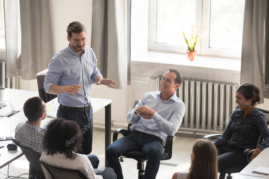 Male mentor talking to workers at diverse group meeting