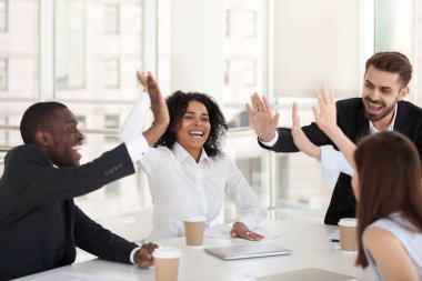 Heyecanlı çeşitli çalışanlar takım toplantısında beşlik çakıyor.
