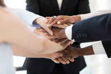 Diverse employees stack hands in pile showing support and unity clipart