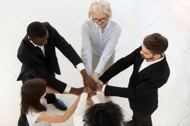 Top view of diverse employees stack hands showing unity