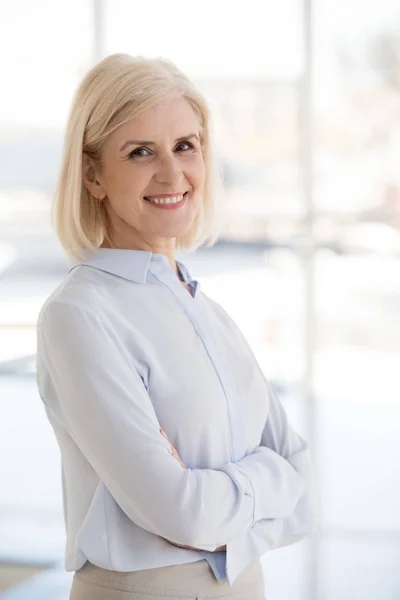 Portrait of smiling mature businesswoman posing with arms crosse