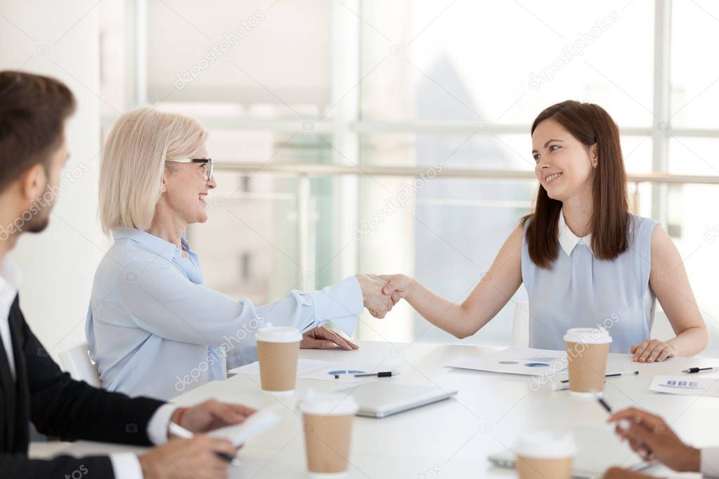 Smiling diverse colleagues handshake during briefing in office