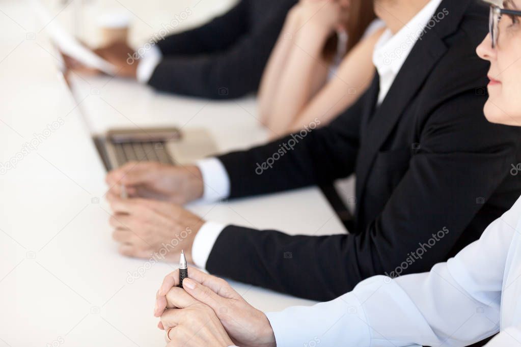 Close up of diverse employees sitting in row at table