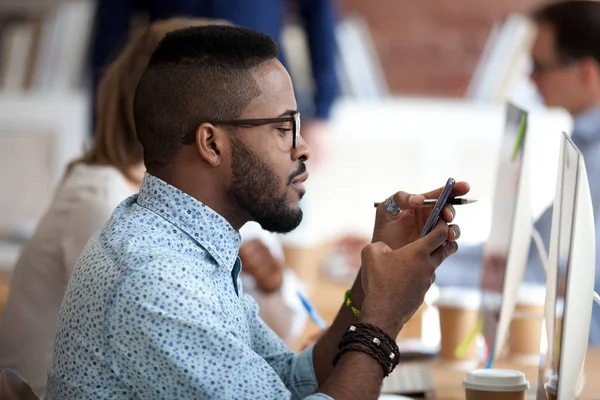 African American male worker using smartphone at work — Stock Photo, Image