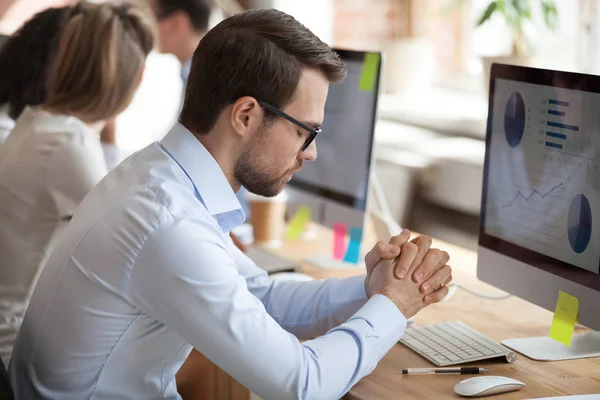 Nervous male employee meditate at workplace trying not to worry