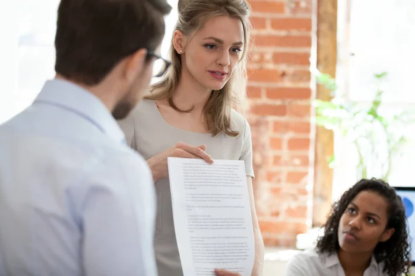 Vrouwelijke coach aanwezig papierwerk aan medewerkers aan vergadering — Stockfoto