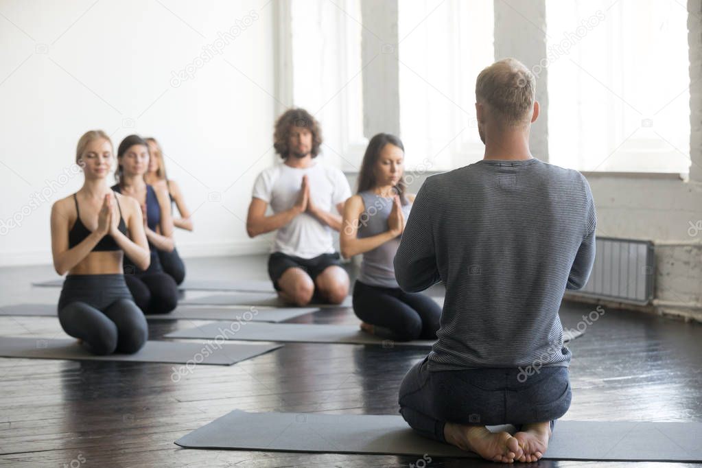 Group of sporty people in vajrasana exercise with instructor