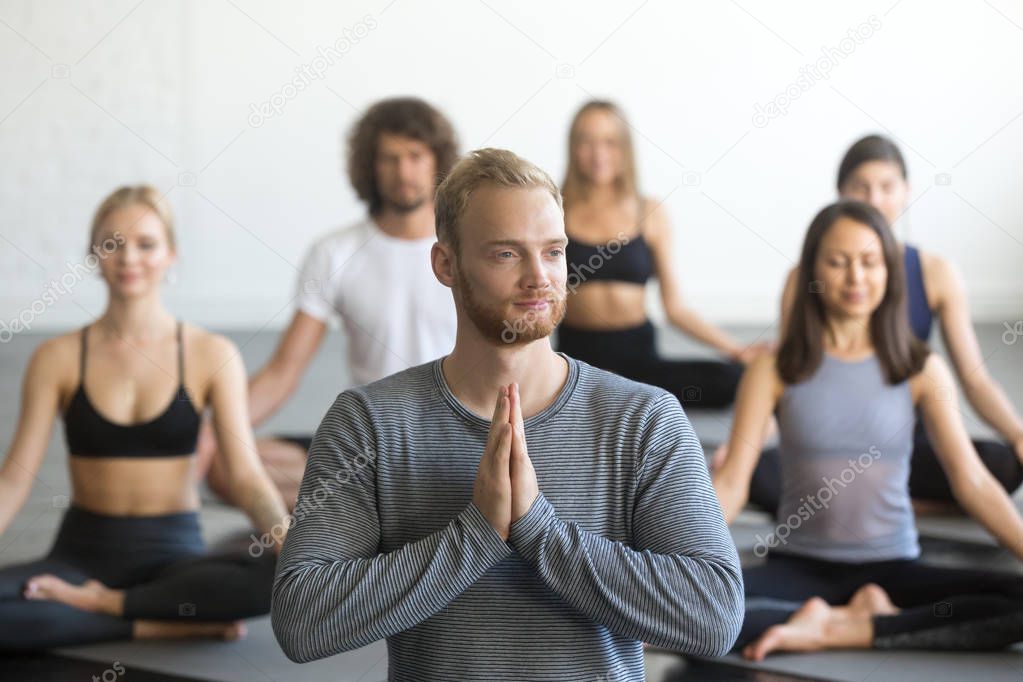 Group of sporty people in Lotus exercise with male instructor