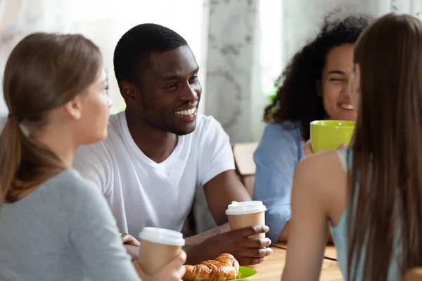 Black man and girls sitting drinking coffe chatting in cafe — Stock Photo, Image
