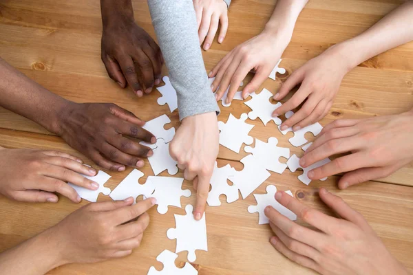 Gros plan mains de diverses personnes assembler puzzle — Photo