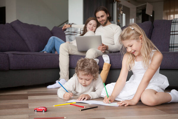 Счастливая молодая семья с детьми проводит свободное время дома
