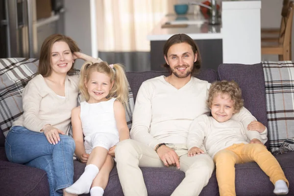 Couple avec de petits enfants assis sur le canapé à la maison — Photo