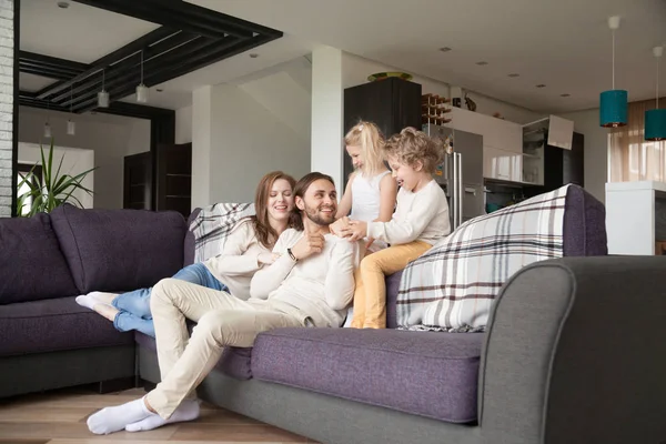 Young family sitting on couch in living room at home