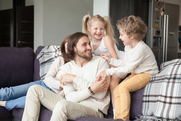 Young family sitting on couch in living room at home
