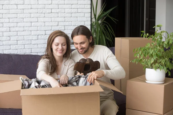 Супружеская пара сидит на диване и распаковывает картонные коробки — стоковое фото