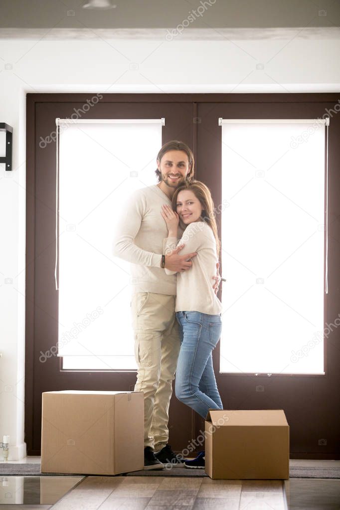 Couple standing with unopened cardboard boxes looking at camera