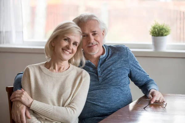 Portrait of smiling aged couple looking at camera embracing — Stock Photo, Image