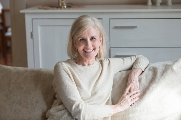 Portrait of smiling aged woman relaxing on cozy couch